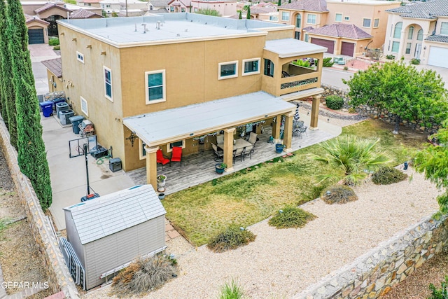 rear view of property with stucco siding, a residential view, an outdoor structure, and a patio