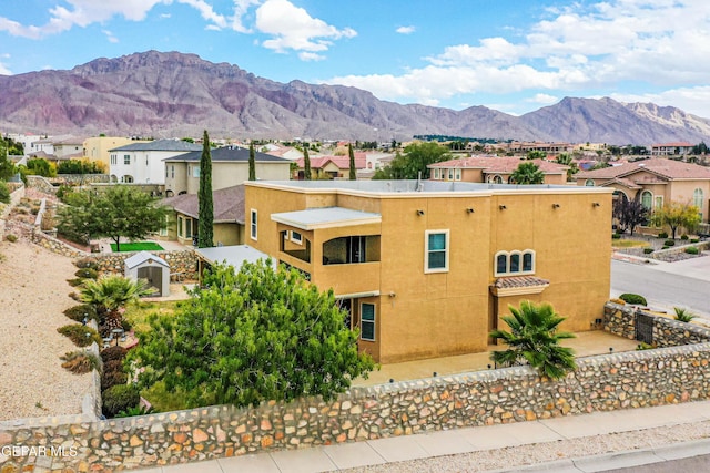 exterior space featuring a residential view, a mountain view, fence, and stucco siding