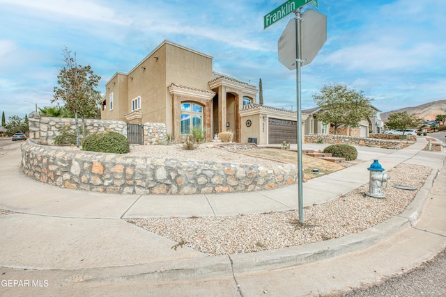 view of front of house featuring driveway, fence, and stucco siding