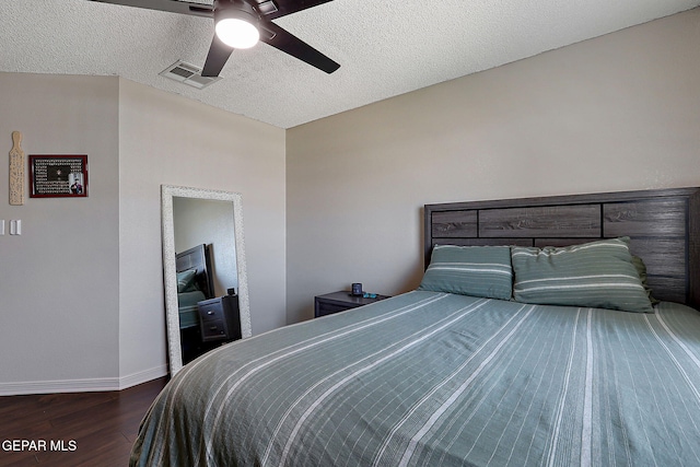 bedroom with visible vents, baseboards, wood finished floors, a textured ceiling, and a ceiling fan