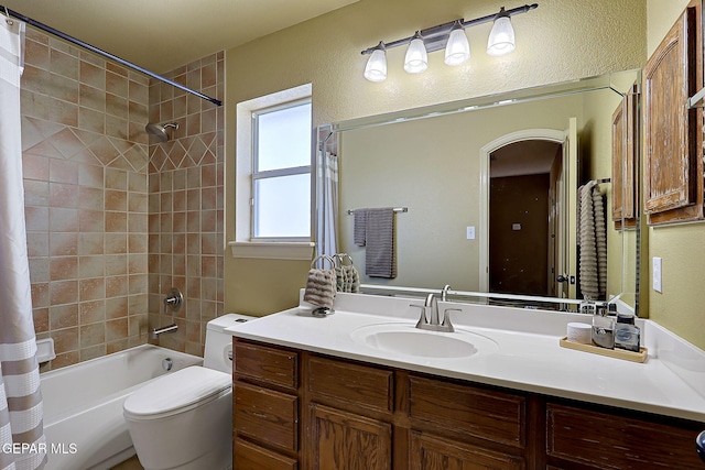 full bathroom with a textured wall, toilet, vanity, and shower / bath combination with curtain