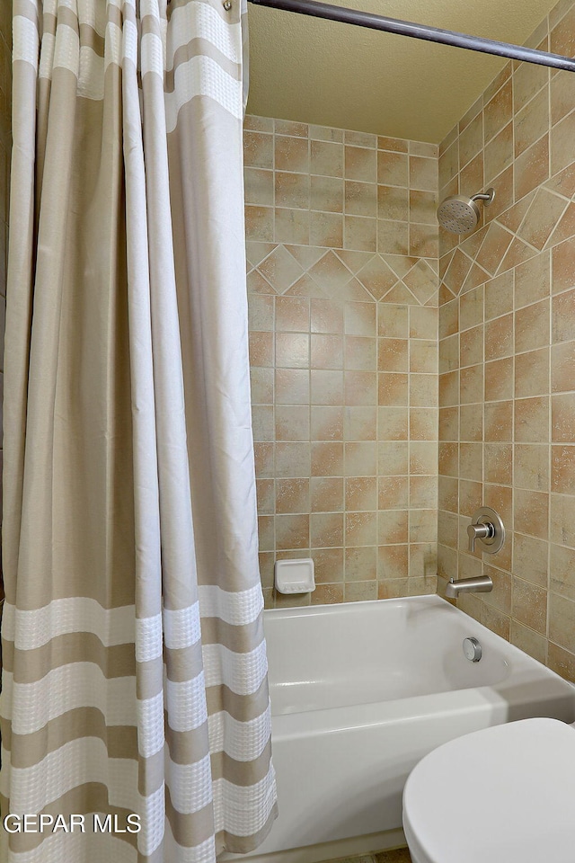 bathroom featuring shower / bath combo with shower curtain and toilet