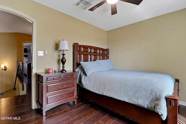 bedroom with a ceiling fan, visible vents, arched walkways, dark wood-style flooring, and a textured ceiling