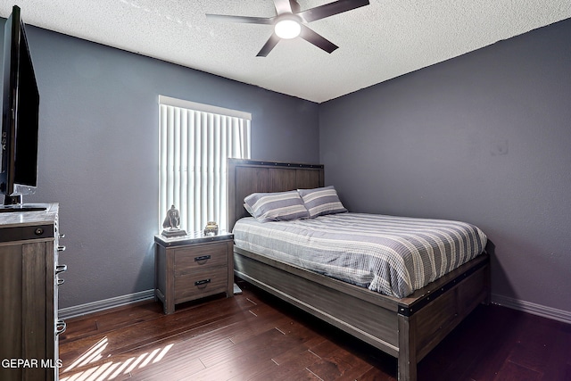 bedroom featuring ceiling fan, a textured ceiling, dark wood-type flooring, and baseboards