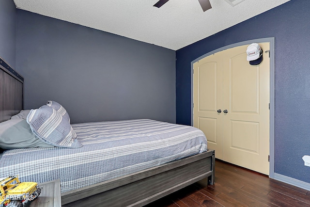 bedroom with ceiling fan, wood finished floors, baseboards, and a textured ceiling