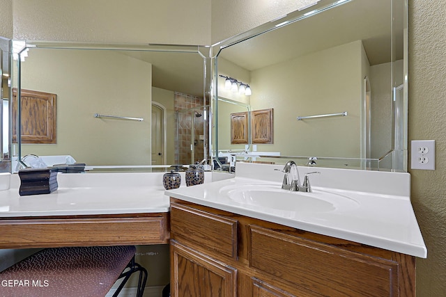 bathroom featuring vanity, a textured wall, and a shower with shower door