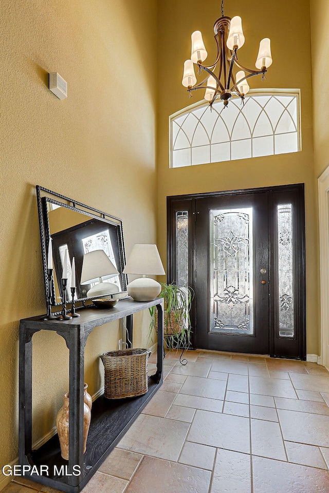 foyer featuring stone tile flooring, a chandelier, and a towering ceiling