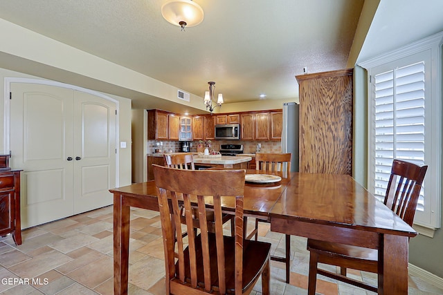 dining room with a notable chandelier, visible vents, and stone finish flooring