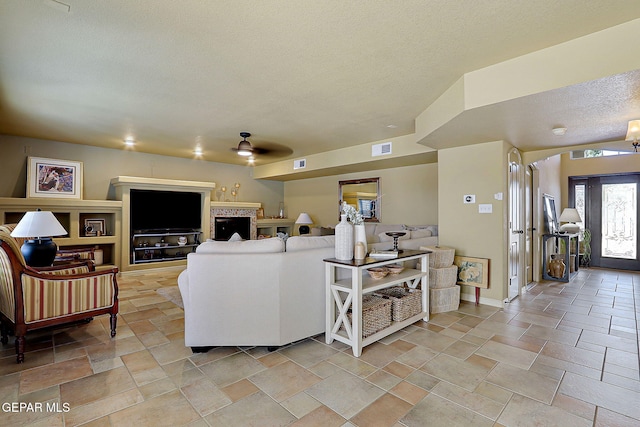 living room with stone finish flooring, baseboards, visible vents, and a textured ceiling