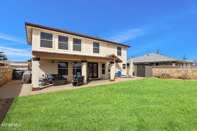 rear view of house featuring stucco siding, a lawn, a storage shed, an outdoor structure, and a patio area