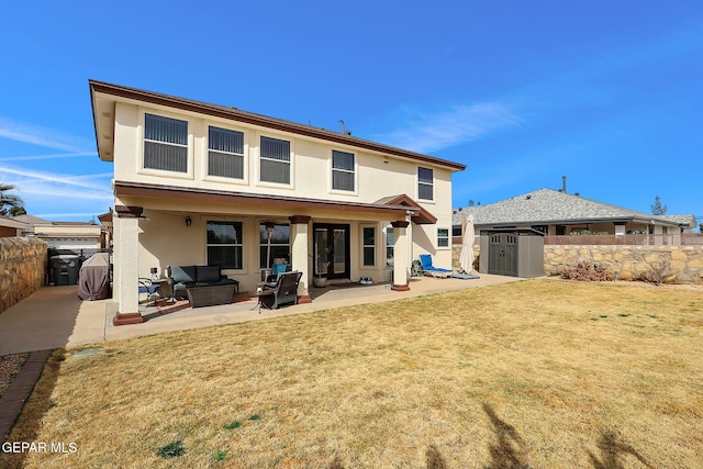 back of house with stucco siding, an outbuilding, a fenced backyard, a shed, and a patio area