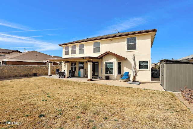 rear view of property featuring fence, stucco siding, a storage shed, a patio area, and an outbuilding