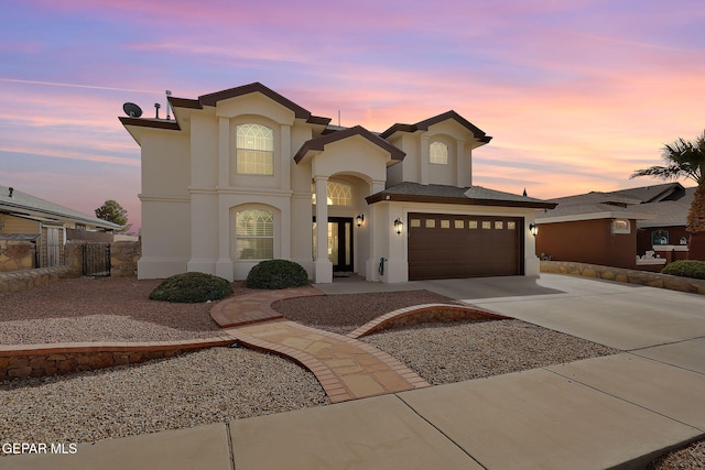 view of front of home featuring stucco siding, a garage, driveway, and fence