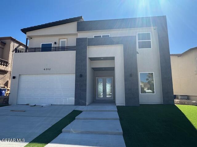 modern home featuring french doors, an attached garage, concrete driveway, and stucco siding