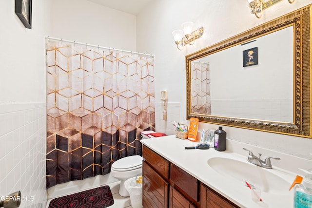 bathroom featuring wainscoting, toilet, tile patterned floors, vanity, and tile walls