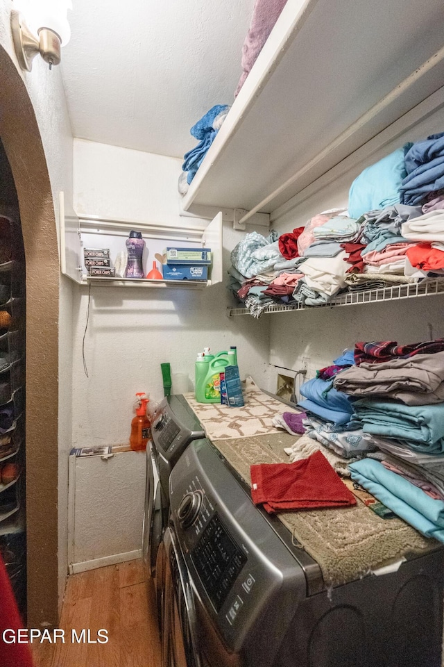 interior space featuring laundry area, washing machine and dryer, baseboards, and wood finished floors