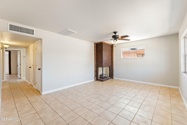 empty room featuring baseboards, a fireplace, visible vents, and ceiling fan