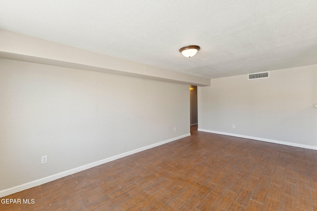 unfurnished room with baseboards, wood finished floors, visible vents, and a textured ceiling