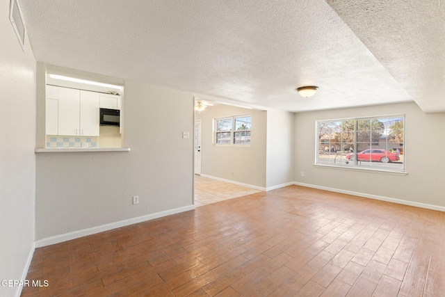 spare room featuring visible vents, baseboards, and light wood finished floors