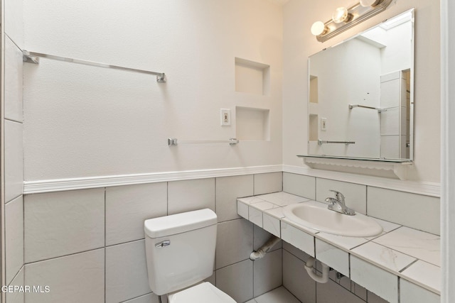 bathroom with toilet, wainscoting, and a sink