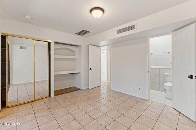 unfurnished bedroom with light tile patterned flooring, visible vents, and a closet