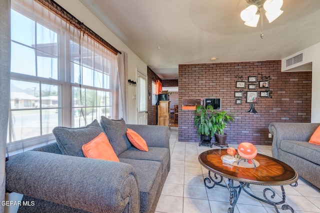 living room featuring light tile patterned flooring, visible vents, brick wall, and a ceiling fan