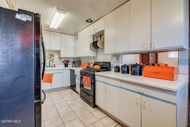 kitchen featuring tasteful backsplash, light countertops, light tile patterned flooring, white cabinets, and black appliances