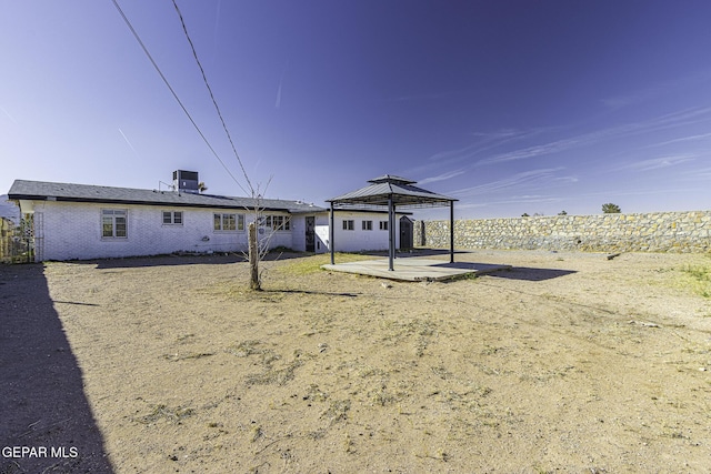 view of front of property with a patio area, brick siding, a gazebo, and central air condition unit