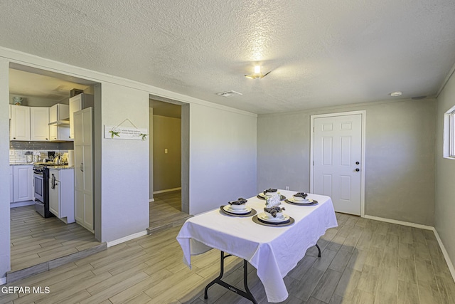 dining space with a textured ceiling, light wood-type flooring, and baseboards