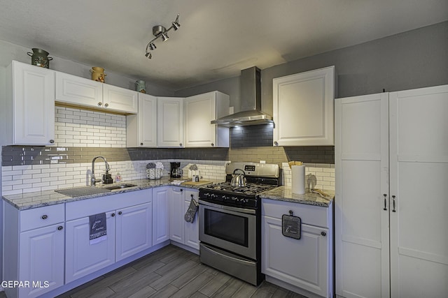 kitchen featuring a sink, white cabinets, wall chimney range hood, stainless steel range with gas cooktop, and tasteful backsplash