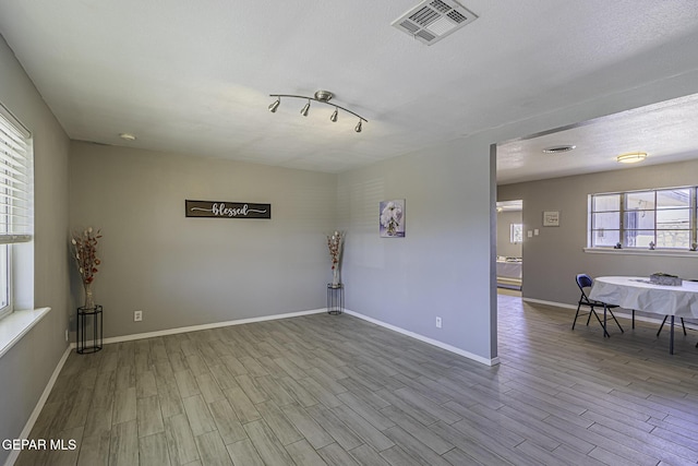 spare room featuring a textured ceiling, wood finished floors, visible vents, and baseboards