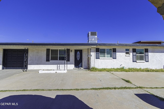 ranch-style house with an attached garage, central AC, and brick siding