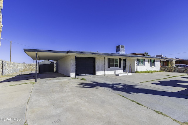 ranch-style house featuring concrete driveway, an attached garage, fence, cooling unit, and an attached carport