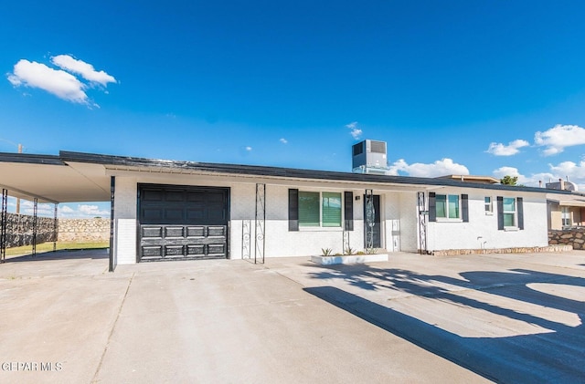 ranch-style home featuring cooling unit, brick siding, driveway, and an attached garage