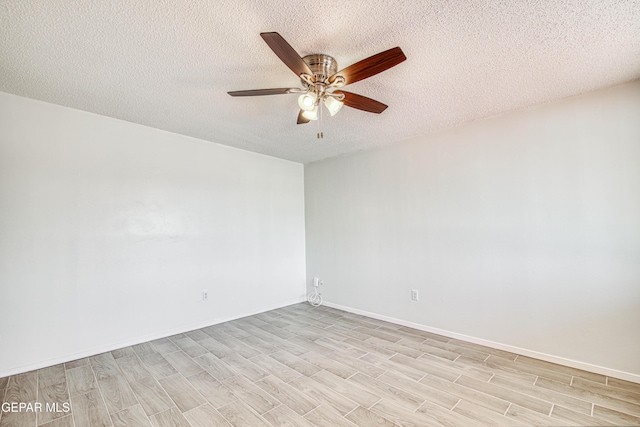 empty room featuring a textured ceiling, light wood-type flooring, a ceiling fan, and baseboards