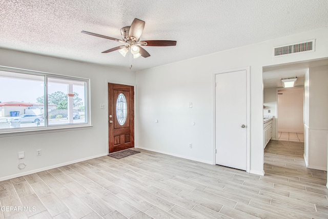 foyer entrance featuring light wood-type flooring, baseboards, visible vents, and a ceiling fan