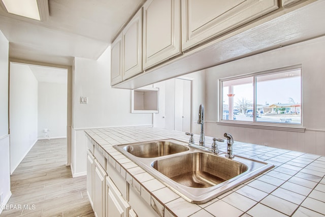 kitchen with tile countertops, a sink, and light wood-style floors