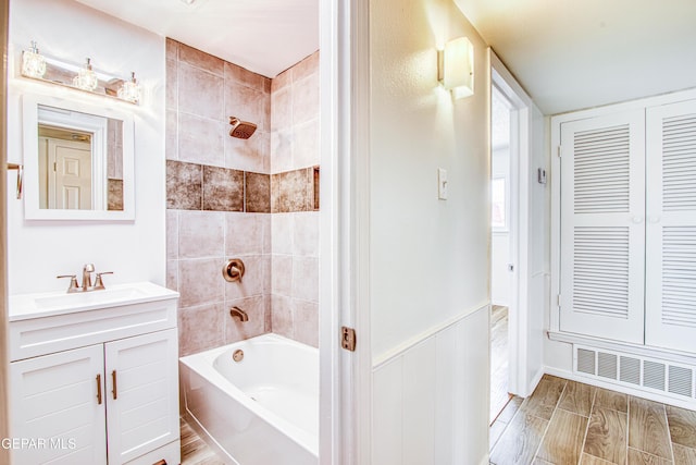 bathroom with bathing tub / shower combination, visible vents, wainscoting, vanity, and wood finished floors