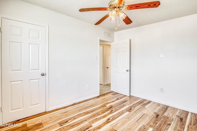 unfurnished room featuring light wood finished floors, visible vents, a ceiling fan, a textured ceiling, and baseboards