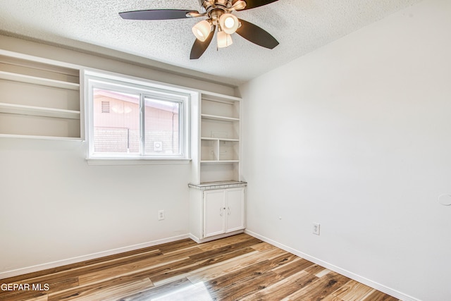 spare room with ceiling fan, baseboards, a textured ceiling, and wood finished floors