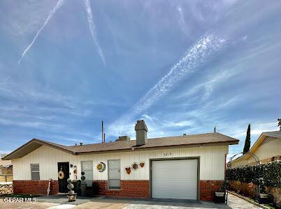 ranch-style home with brick siding, a chimney, and an attached garage