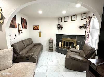 living room featuring recessed lighting, arched walkways, marble finish floor, and a tile fireplace