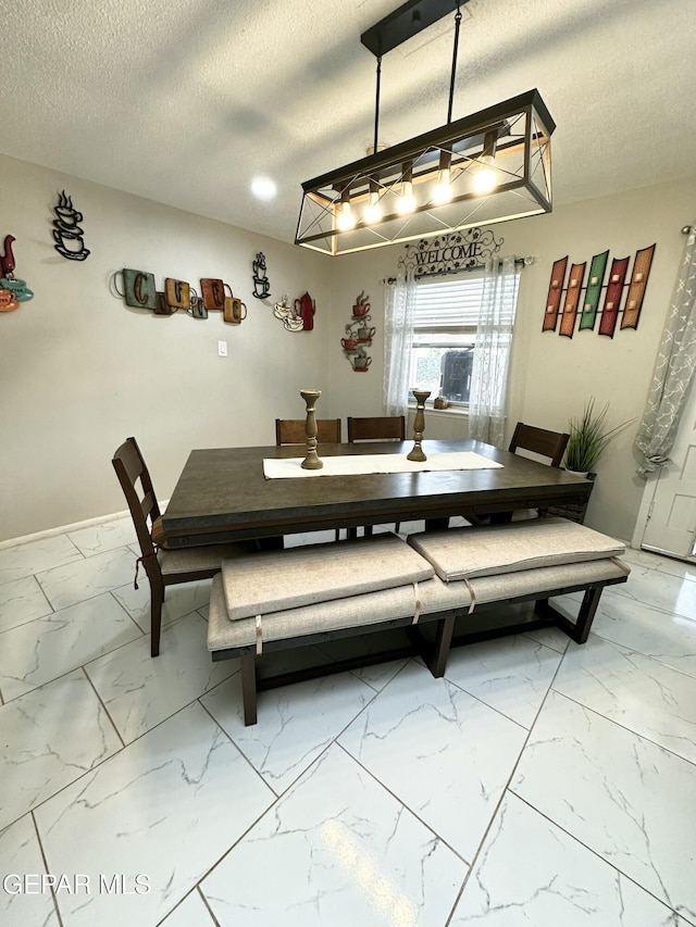 dining area with baseboards, a textured ceiling, and marble finish floor