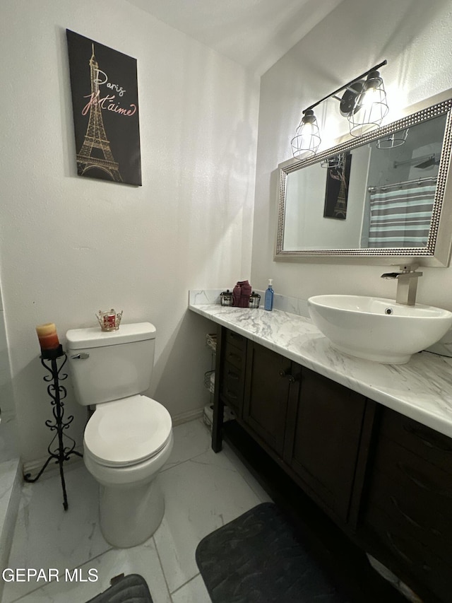 bathroom with toilet, marble finish floor, and vanity