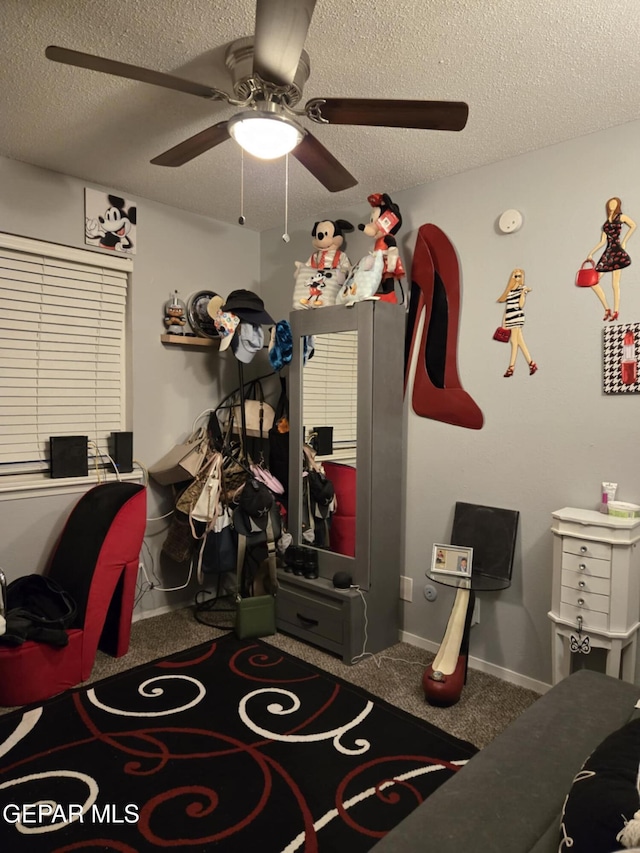 interior space featuring baseboards, a textured ceiling, and ceiling fan