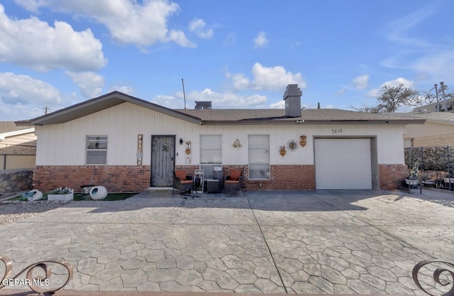 ranch-style home with concrete driveway, an attached garage, brick siding, and a chimney