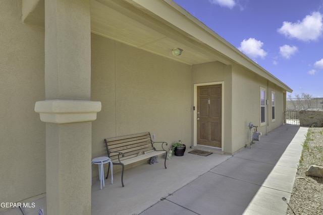 entrance to property with a patio, fence, and stucco siding