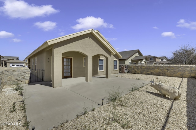 rear view of house featuring stucco siding, a patio, and fence