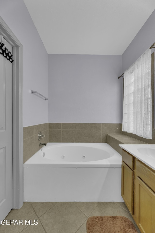 bathroom with a jetted tub, vanity, and tile patterned flooring