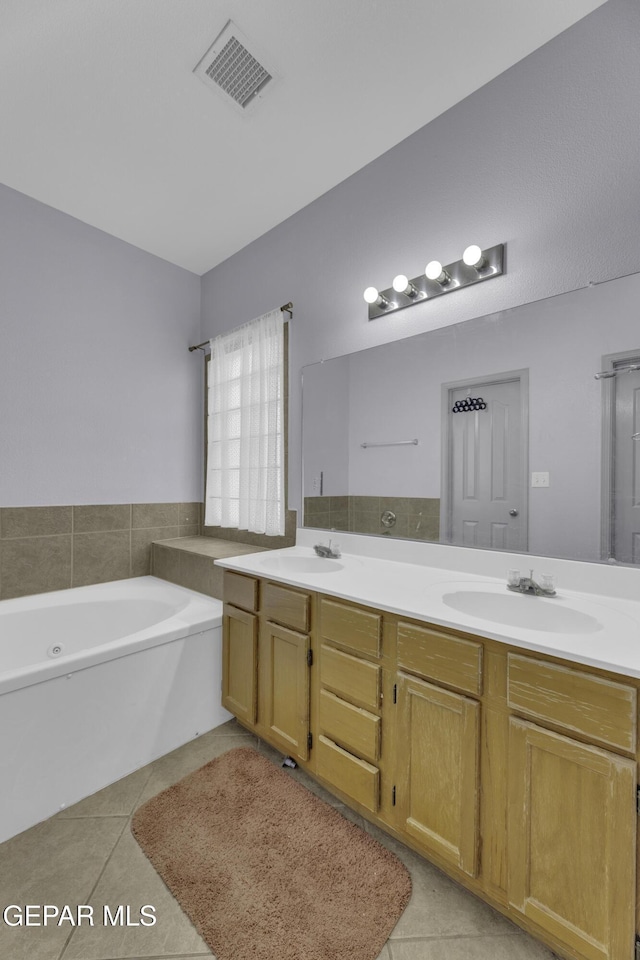 bathroom featuring tile patterned flooring, visible vents, double vanity, a bath, and a sink